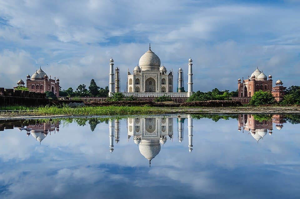The Taj Mahal, its garden pavilions, and their reflections on still water in Agra.